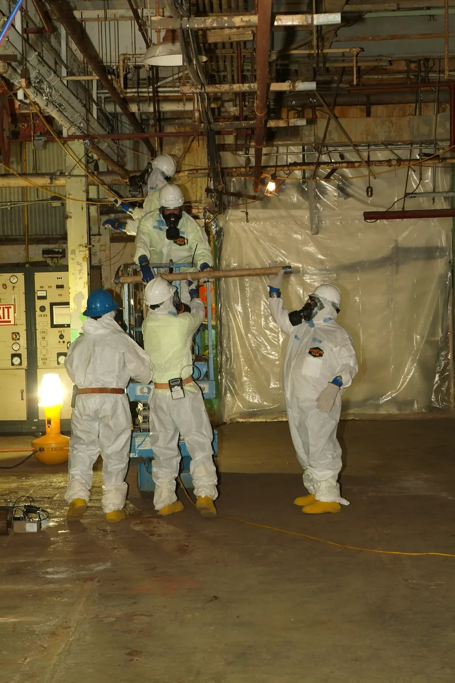Équipe en combinaison de protection lors d'une intervention de désamiantage en milieu industriel (photo d'illustration)